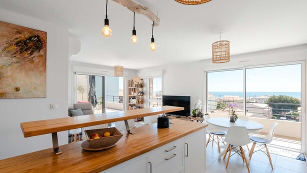 Een moderne keuken met een houten aanrecht, een ingebouwde televisie en een eethoek met een ronde tafel en stoelen.