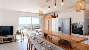 Een moderne keuken met een houten kookeiland, roestvrijstalen apparatuur en een groot raam met uitzicht op de stad.