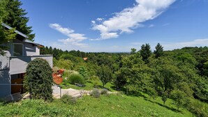 Una casa moderna con vistas a un paisaje verde exuberante y colinas distantes.