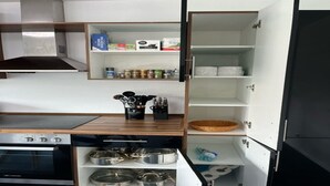 Eine kompakte Küche mit Einbauofen, Spüle und Regalen zur Aufbewahrung.