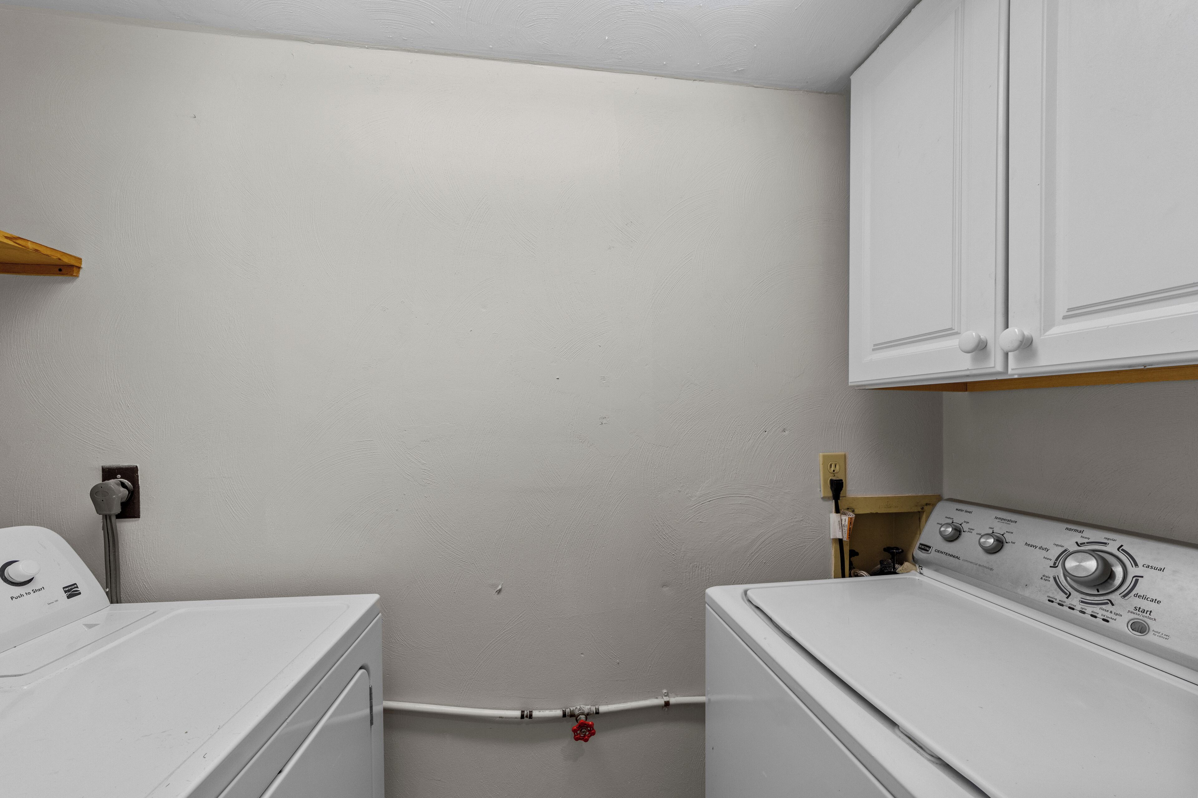 A laundry room with a washing machine, dryer, and a control panel.