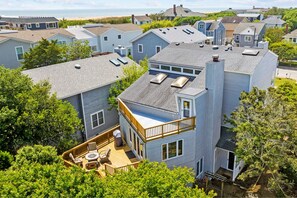 A residential area with multiple houses, a wooden deck with outdoor furniture, and a view of the ocean. - Enjoy your vacation at the Triple Wave Rider (Virginia Beach)
