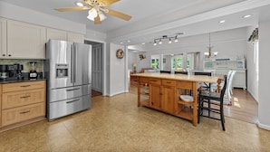 A spacious kitchen with a central island, stainless steel appliances, wooden cabinets, and a ceiling fan. - Enjoy your vacation at the Triple Wave Rider (Virginia Beach)