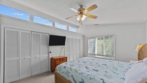 A bedroom with a bed, a ceiling fan, a wardrobe, a window with blinds, and a television on the wall. - Enjoy your vacation at the Triple Wave Rider (Virginia Beach)