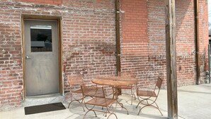 Un edificio de ladrillo con una puerta de metal y una mesa redonda con sillas afuera.