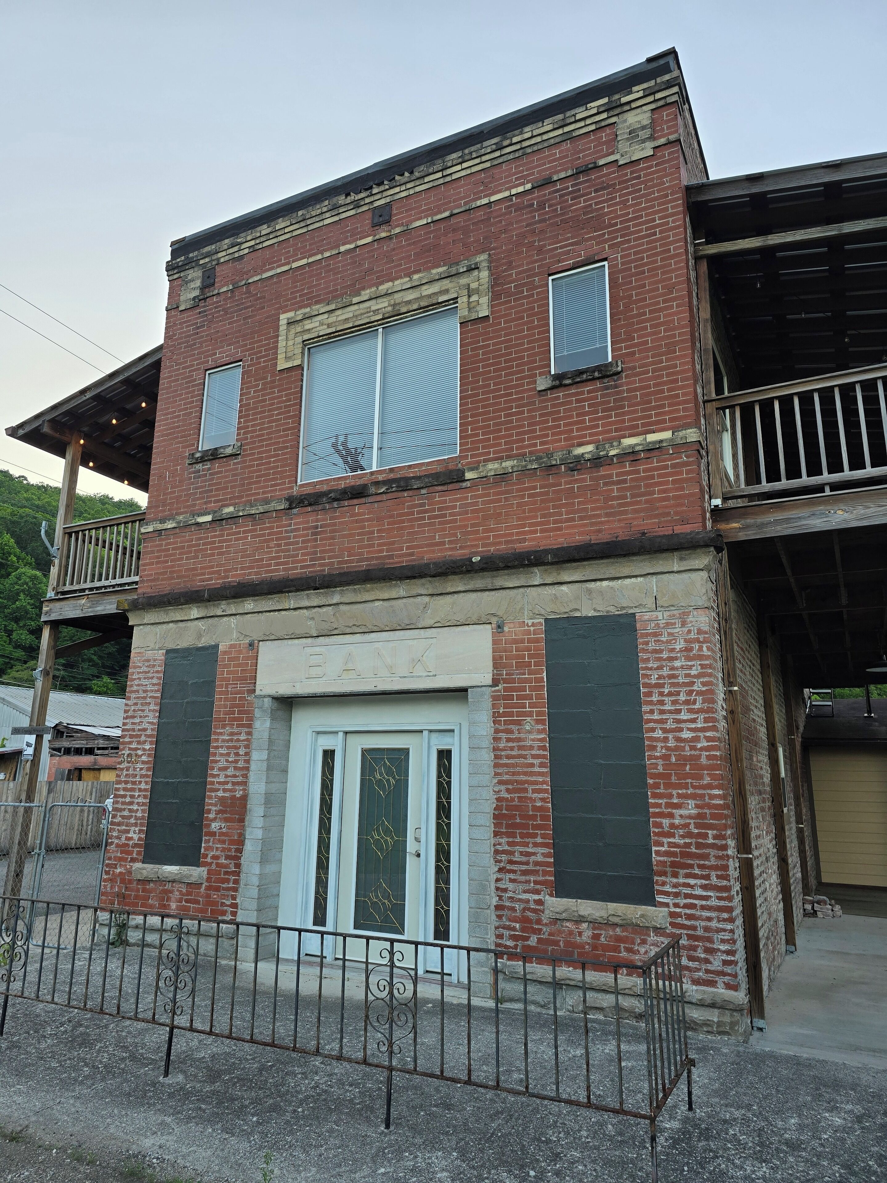 A two-story building with a brick facade, a white door, and a balcony with a metal railing.