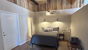 Un dormitorio con cama, ventilador de techo y mesita de noche.