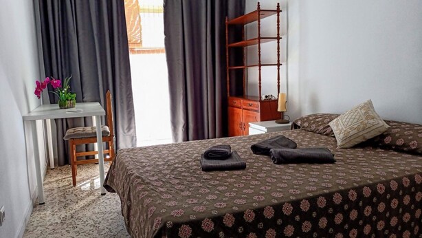Un dormitorio ordenado con una cama, un escritorio pequeño y una silla.