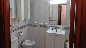 Un baño con inodoro, bidé, lavamanos y espejo.