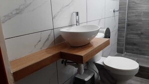 A bathroom with a white marble sink, a wooden countertop, a modern faucet, and a white toilet. - Gran Imperial Avenida (Tumbes)