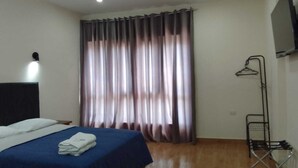 A bedroom with a bed, a hanging clothes rack, and a window with curtains. - Gran Imperial Avenida (Tumbes)