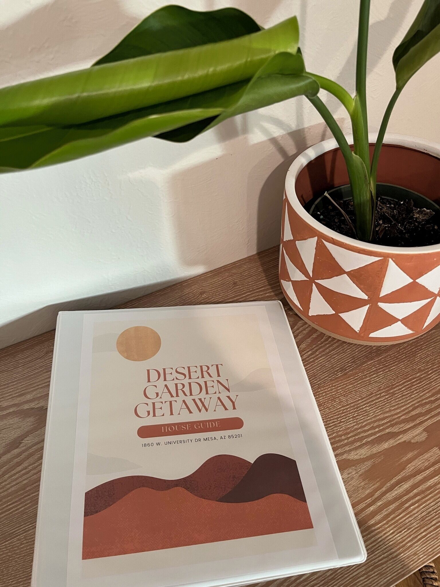 A book titled 'Desert Garden Getaway House Guide' placed on a wooden surface next to a potted plant.