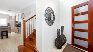 A modern kitchen with stainless steel appliances, a wooden staircase, and decorative wall art. - Bennett’s Beach Townhouse (Hawks Nest)