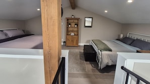 Ein Schlafzimmer mit zwei Betten, einem Holzschrank und einem kleinen Schreibtisch.