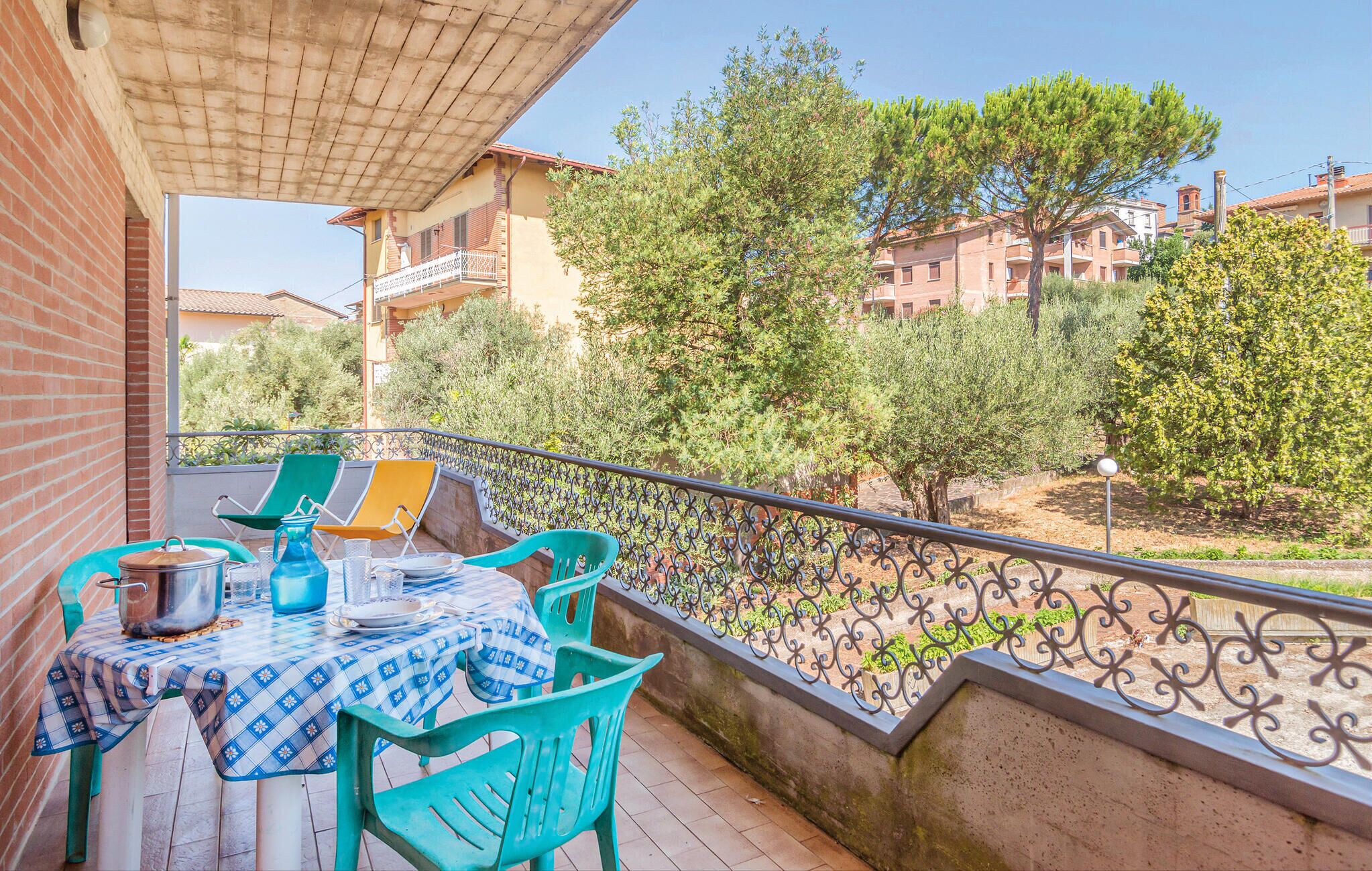 Ein Balkon mit Esstisch, umgeben von Grünpflanzen und Gebäuden im Hintergrund.