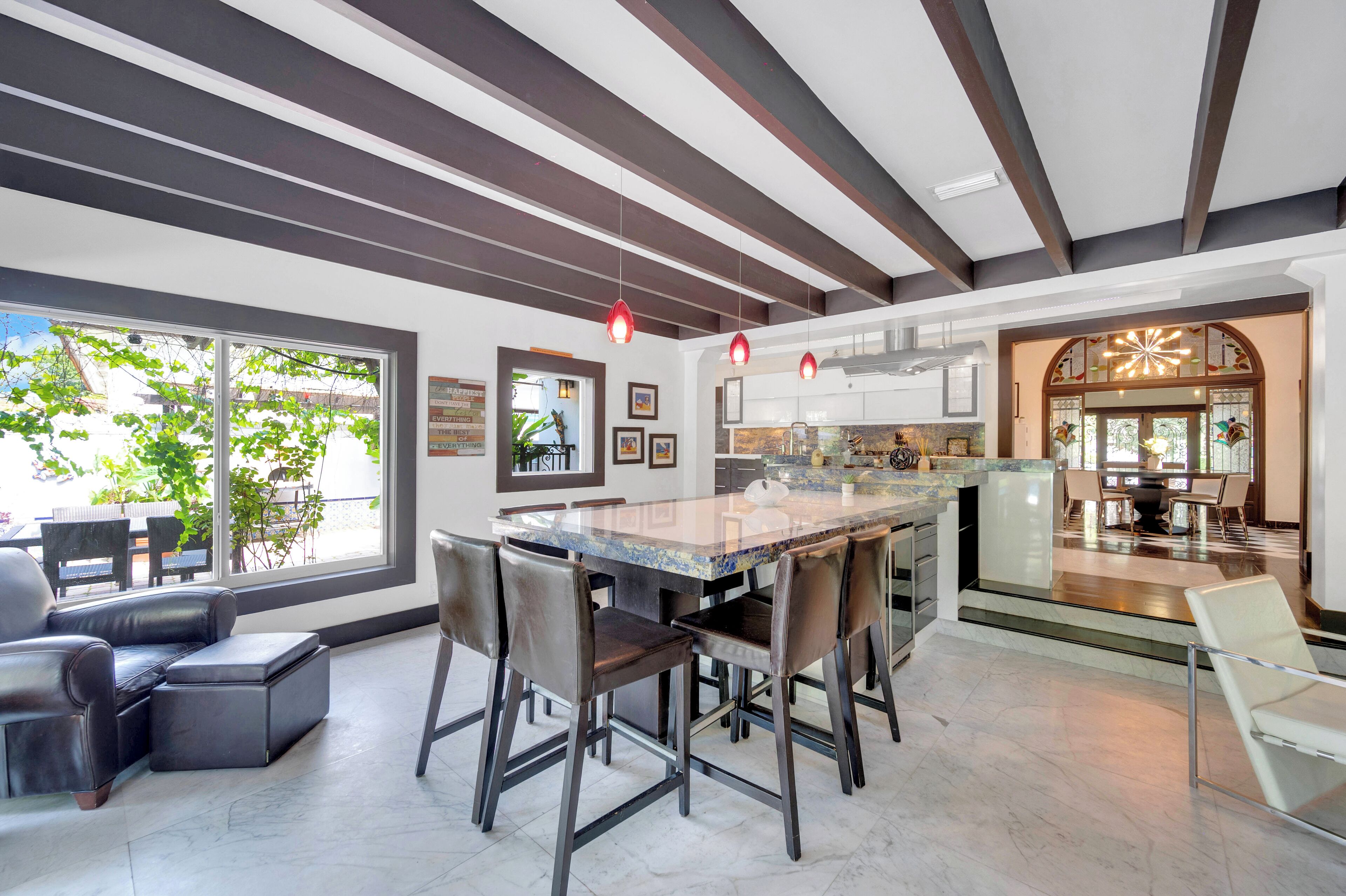 A modern kitchen with a large island, bar stools, and a dining area with a sofa and chairs.