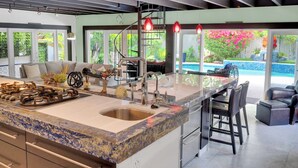 A modern kitchen with a large island, stainless steel appliances, and a view of a swimming pool. - Magnificient Tropical Pool House Miami South Brickell - Spa / Heated Pool (Miami)