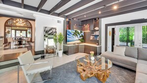 A modern living room with a glass coffee table, a sofa, and a TV. There is a dining area in the background with a table and chairs. - Magnificient Tropical Pool House Miami South Brickell - Spa / Heated Pool (Miami)