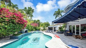 A swimming pool with a tiled edge, surrounded by lounge chairs and a covered patio area. - Magnificient Tropical Pool House Miami South Brickell - Spa / Heated Pool (Miami)