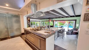 A modern kitchen with a large island, stainless steel appliances, and a view of the outdoor patio area. - Magnificient Tropical Pool House Miami South Brickell - Spa / Heated Pool (Miami)