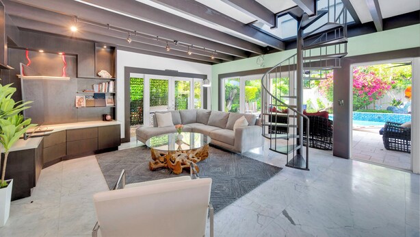 A modern living room with a curved sofa, a glass coffee table, and a staircase leading to an outdoor area. - Magnificient Tropical Pool House Miami South Brickell - Spa / Heated Pool (Miami)
