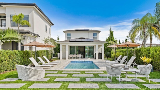 A modern house with a swimming pool, outdoor seating, and solar panels. - The Villa Tranquility with Private Pool (Kissimmee)
