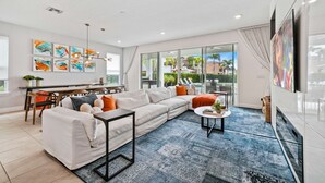 A modern living room with a sectional sofa, a coffee table, and a dining area with a table and chairs. - The Villa Tranquility with Private Pool (Kissimmee)