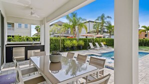 A patio with a glass-top table and chairs, a pool, and a view of the neighborhood. - The Villa Tranquility with Private Pool (Kissimmee)