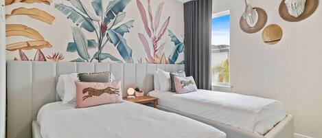 A hotel room with two beds, a large wall mural, and a window with curtains.