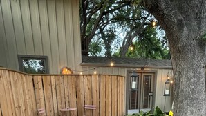 A patio with a stone floor, a table with chairs, and a small fire. - NEW! Historic Guest Home on Main - Heart of Town (Salado)