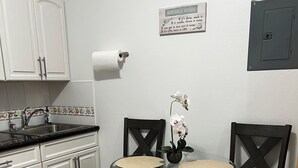 A kitchen with white cabinets, a sink, a glass table with chairs, and a kitchen rules sign on the wall. - Get away to Green Pastures #6 .10 min drive to Beach, Great for weekend getaways (Nassau)