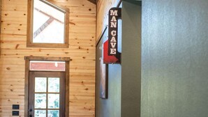 A wooden interior hallway with a door leading to a room, a window, and a directional sign. - Cozy Lodge at Ward Creek Ranch close to interstate and wedding venues.  (Simms)