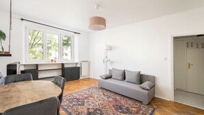 Un salon moderne avec un canapé gris, une table à manger en bois et un tapis à motifs.