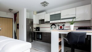 A modern kitchen with white cabinets, a stainless steel refrigerator, and a coffee maker.