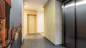 A hallway with a wooden door, a tiled floor, and a wall with a mural.