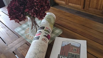 A rolled-up map with a printed sign reading "The Bank at Coal Creek" and a small vase with red flowers on a wooden table.