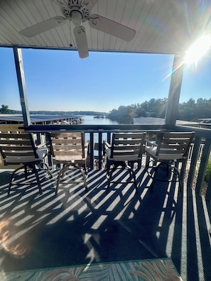 A covered outdoor seating area with a view of a lake and dock.