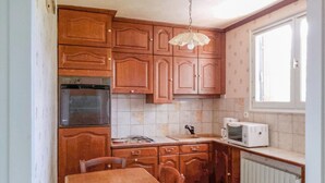 Una cocina con armarios de madera, estufa, microondas y ventana.
