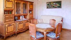 Un comedor con un armario de madera, una mesa redonda de vidrio y sillas de mimbre.