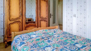 Un dormitorio con un armario de madera, una cama con colcha estampada y papel tapiz floral.