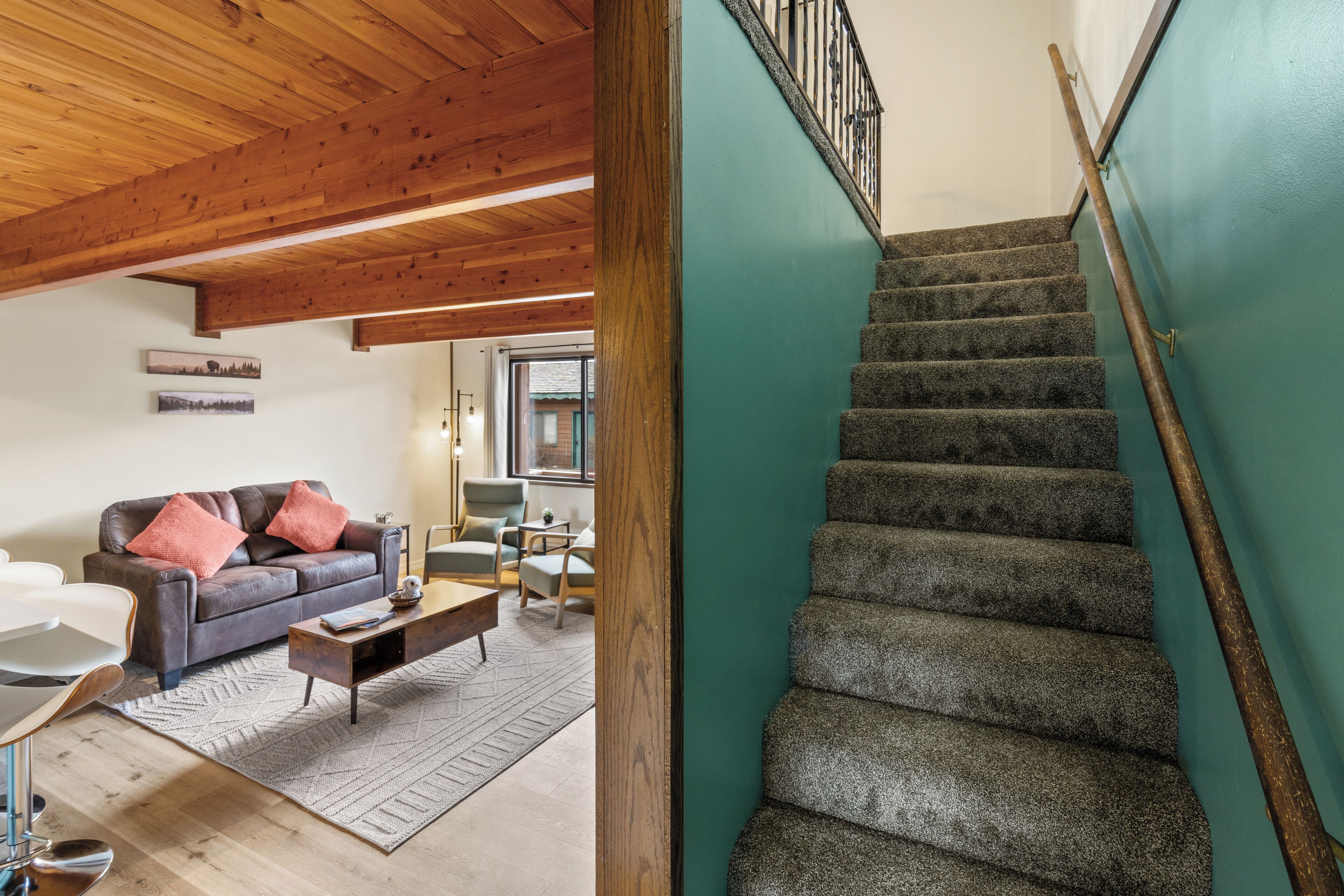 A staircase with a wooden handrail and carpeted steps, leading to an upper floor.