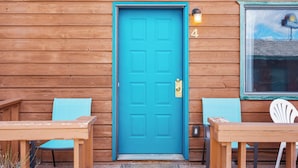 A wooden building with a turquoise door, numbered 4, and two wooden tables with chairs. - Owl's Nest (West Yellowstone)