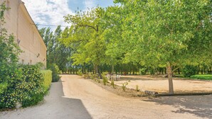 A gravel path leading to a building with a large tree in the foreground. - 3 bedroom lovely apartment in Le Sambuc (Le Sambuc)