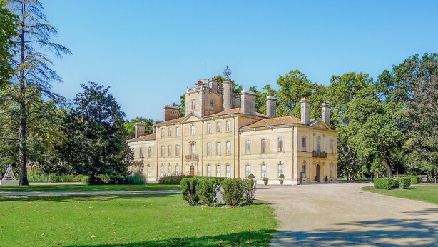 A large, historic building with multiple stories and a symmetrical facade, surrounded by well-maintained gardens and trees. - 3 bedroom lovely apartment in Le Sambuc (Le Sambuc)