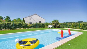 A swimming pool with inflatable rings and a white chair, surrounded by well-maintained grass and a building in the background. - 3 bedroom lovely apartment in Le Sambuc (Le Sambuc)