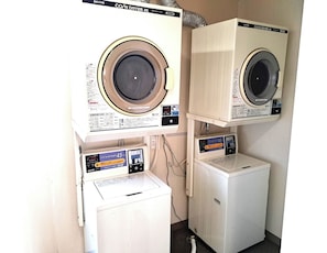 Two stacked washing machines, a dryer, and a control panel with instructions.