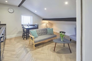 Un appartement moderne de style « loft » comprenant un coin repas, un canapé et une petite table ronde agrémentée d  ’un vase.