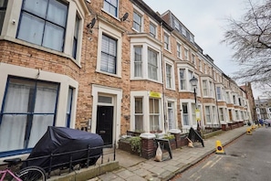 A row of terraced houses with a sign indicating a property for sale.