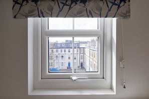 A window with a view of buildings and a blue car outside. - Grace’s Loft - Central Scarborough 1 Bed Apartment (Scarborough)