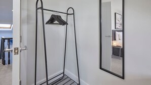 A room with a metal drying rack, a mirror on the wall, and a door leading to another room. - Grace’s Loft - Central Scarborough 1 Bed Apartment (Scarborough)